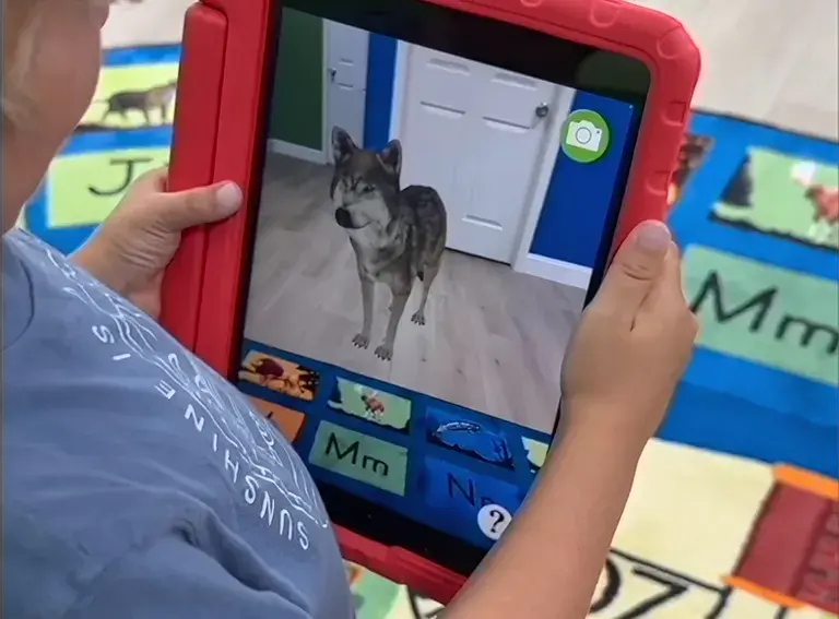 Child holdding a tablet computer featuring the Rugs alive app showing an augmented reality dog standing on the carpet