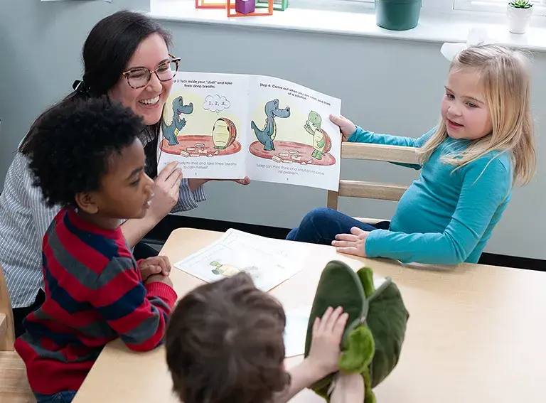 Teacher showing a picture book to a group of preschool children