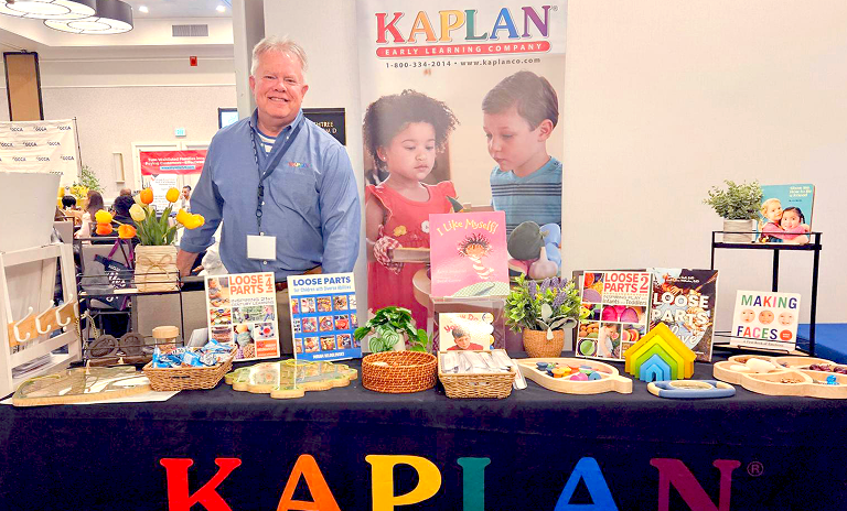 Sales representative standing behind a table full of Kaplan products