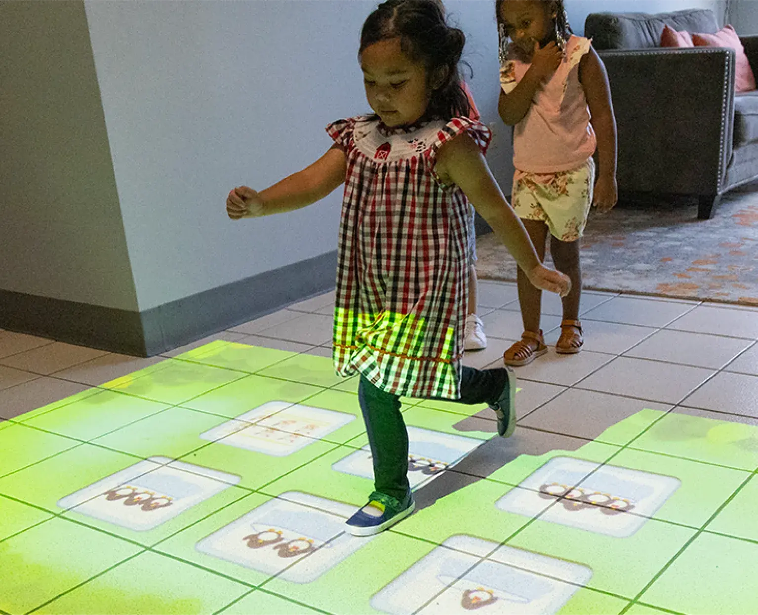 Young preschool girl playing with an interactive game projected onto the floor