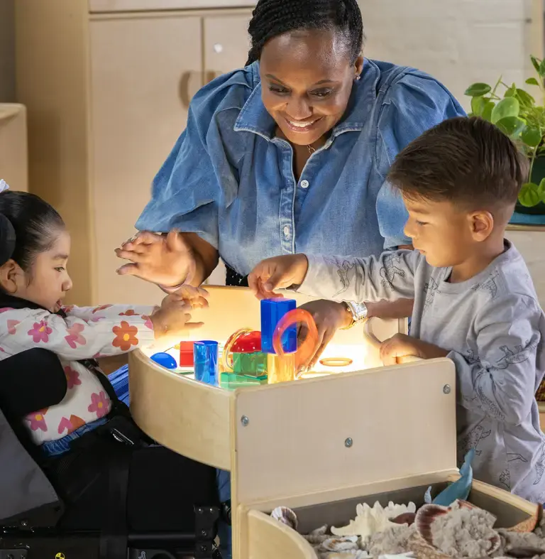 Teacher and special needs children playing around the Carolina Connections Discovery Table